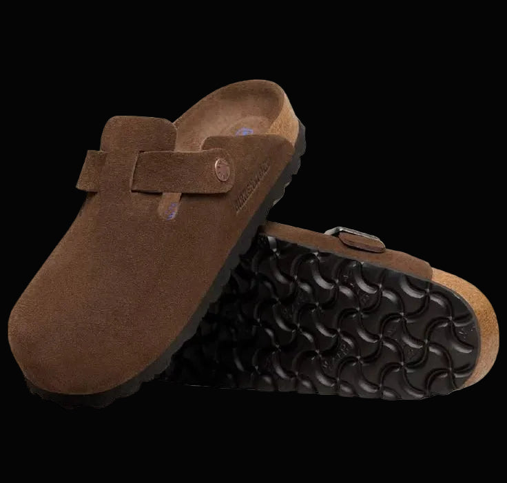 Brown suede clogs with black soles on a white background
