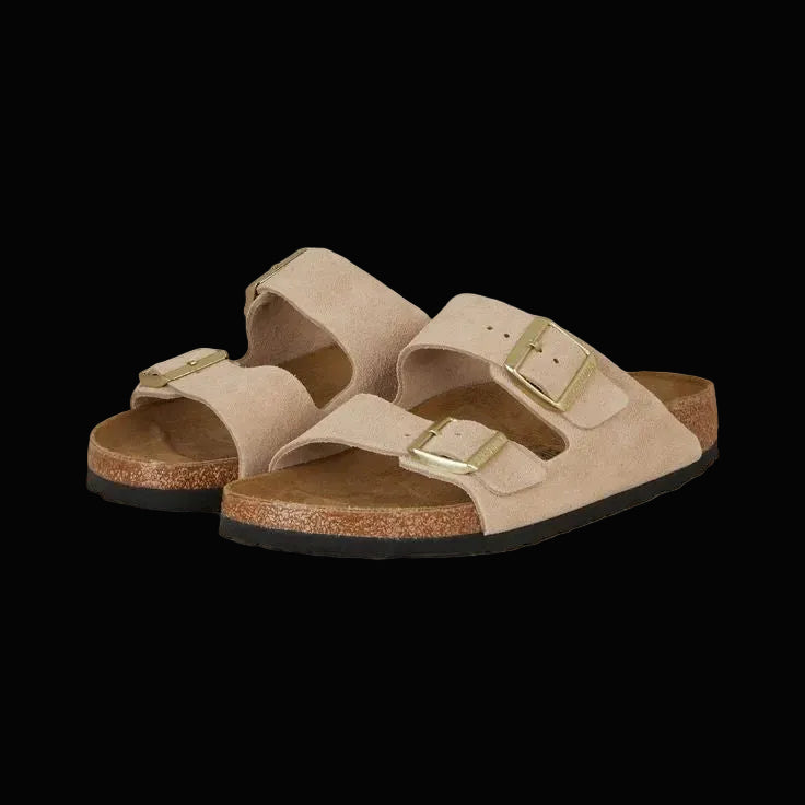 Pair of beige sandals with gold buckles on a white background