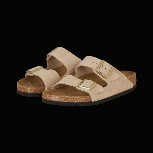 Pair of beige sandals with gold buckles on a white background